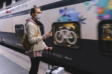 Frau mit Maske vor Zug